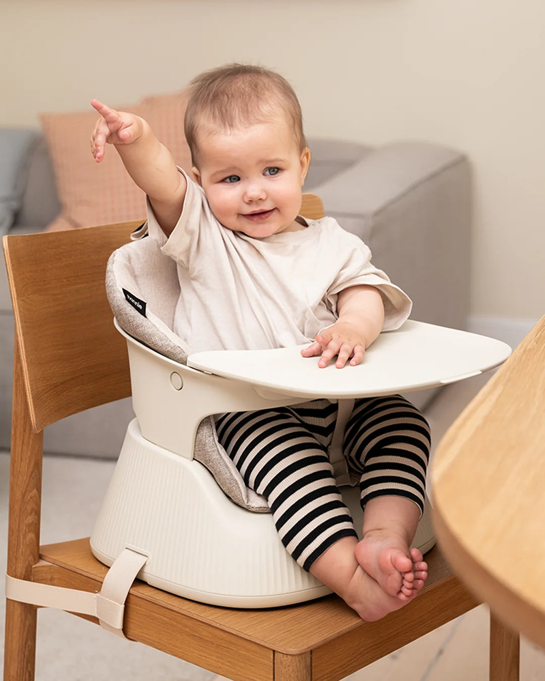 Baby pointing excitedly from the Hannie Portable High Chair at the family table